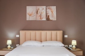 A bedroom with a bed, two bedside tables, and three wall-mounted paintings. - Coastal Living Retreat | 2BR in Lungomare by PikHost (Vlorë)