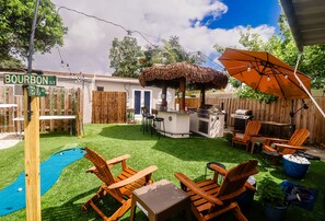 Ein Garten mit Grillplatz, Sitzgelegenheiten im Freien und einem Pool.