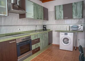 Een kleine keuken met een inbouwoven, een wasmachine en een magnetron.