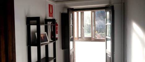 A hallway with a bookshelf, a fire extinguisher, and a door leading to a balcony.