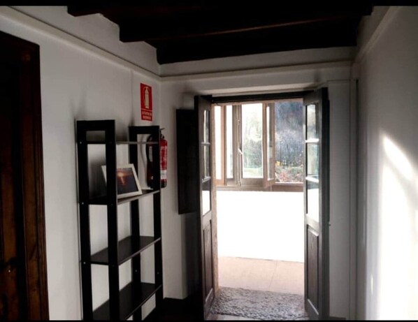A hallway with a bookshelf, a fire extinguisher, and a door leading to a balcony.