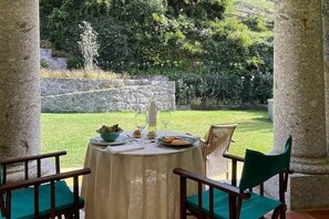 A table set for two with a view of a well-maintained garden and stone wall. - Family house with pool at Quinta da Agrela (Portugal) (Vade (São Pedro))