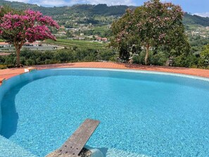 A clear blue pool with a wooden edge, surrounded by lush greenery and hills in the background. - Family house with pool at Quinta da Agrela (Portugal) (Vade (São Pedro))