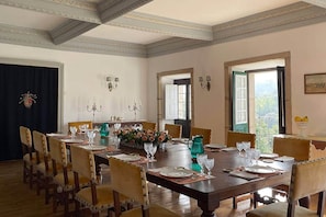 Ein Esszimmer mit großem Tisch, Stühlen und Blick ins Freie.