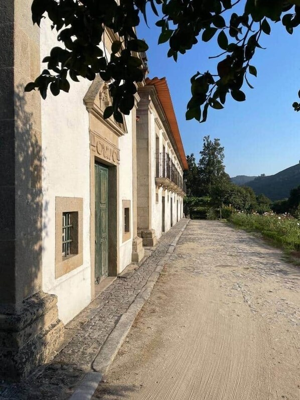 Ein Gebäude mit einer Stein-Fassade, einer grünen Tür und einem Kopfsteinpflasterweg, der davorhin führt.