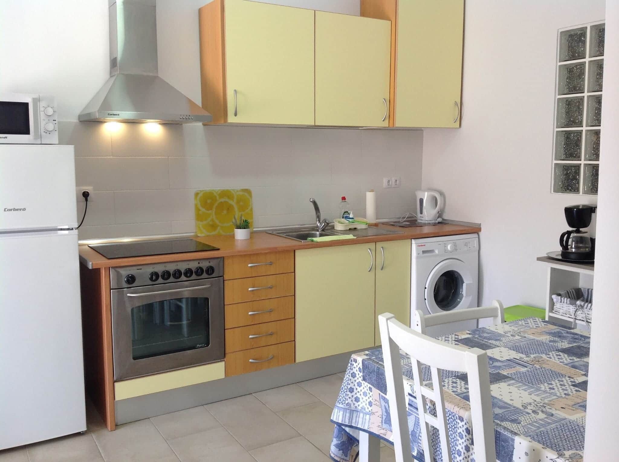 A compact kitchen with a stove, oven, microwave, and washing machine.