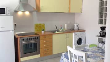 A compact kitchen with a stove, oven, microwave, and washing machine.