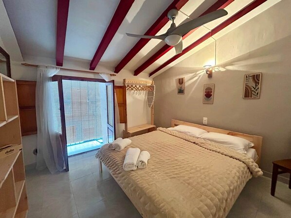 A bedroom with a bed, a ceiling fan, a window with blinds, and a door. - Village house with terraces and a barbecue in Teulada, Costa Bla (Teulada, Spain)