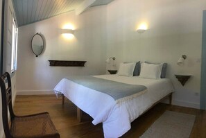 A bedroom with a bed, two wall sconces, a mirror, a wooden chair, and a rug. - Private suite with views · Quinta da Agrela (Portugal) (Vade (São Pedro))