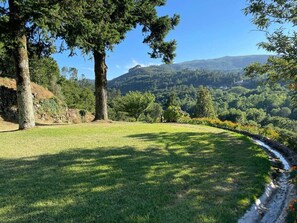 A grassy field with a stream, trees, and a hilly landscape in the background. - Private suite with views · Quinta da Agrela (Portugal) (Vade (São Pedro))