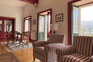 A room with a dining table, two striped armchairs, a lamp, and a view of the outdoors. - Private suite with views · Quinta da Agrela (Portugal) (Vade (São Pedro))