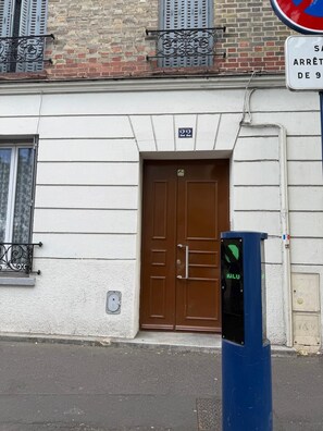 A building with a brown door, a blue traffic signal, and a no parking sign. - BEAUTIFUL 2-BEDROOM APARTMENT AT LA POSTE, 22 AV. JEAN JAURES (Drancy)
