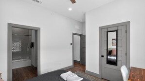 Une chambre d’hôtel moderne, équipée d’un lit, d’une petite table et d’une porte donnant sur une autre pièce.