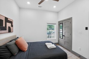 Ein Schlafzimmer mit einem Bett, Kissen, einem Fenster und einer Tür.
