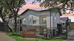 Un bâtiment moderne à deux étages, doté d’une clôture en métal, d’une enseigne indiquant « Rhône » et d’une pelouse devant.