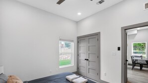 A bedroom with a bed, a window, a door, and a view of an outdoor area. - Modern 2-bedroom featuring spacious open-concept (Austin)