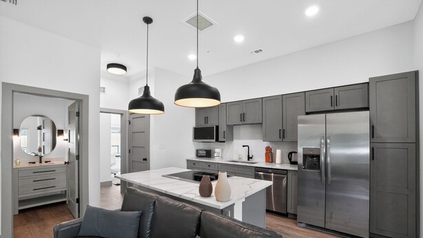 A modern kitchen with grey cabinets, stainless steel appliances, and pendant lighting. - Modern 2-bedroom featuring spacious open-concept (Austin)