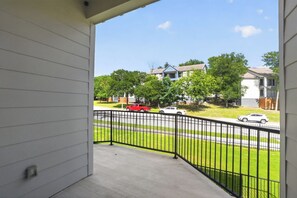 A balcony with a view of a residential street, a black metal fence, and houses in the background. - Elegant 2-bedroom with upscale finishes throughout. (Austin)