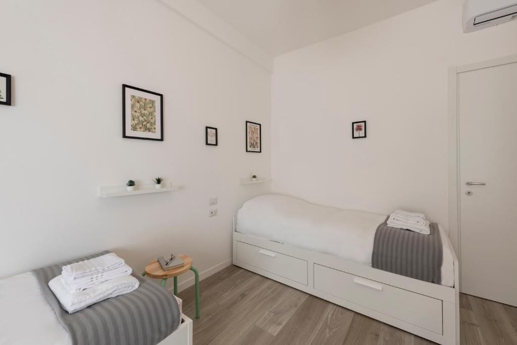 A modern bedroom with a bed, a small bedside table, a chair, and a wardrobe.