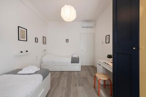 Een minimalistische slaapkamer met een bed, bureau en stoel, een hanglamp en een deur.