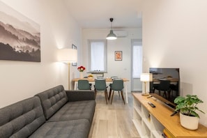 A modern living room with a sofa, dining table, chairs, and a TV. - Caracciolo, 28 - Ampio per 5, ottima posizione  (Milano)