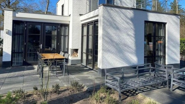 A modern house with a patio, large windows, and a brick exterior.