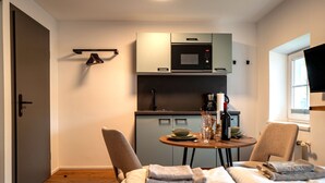 Quarto de hotel compacto com cozinha compacta, área de refeições com mesa e cadeiras, e uma cama com toalhas.