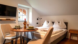 Een slaapkamer met een bed, nachtkastje en een aan de muur bevestigde televisie.