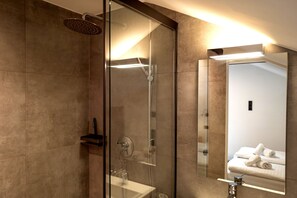 Un baño moderno con cabina de ducha de vidrio, un espejo grande y un toallero visible.
