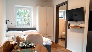 Een slaapkamer met een bed, nachtkastje en een aan de muur bevestigde televisie.