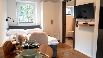 Ein Schlafzimmer mit Bett, Nachttisch und einem an der Wand befestigten Fernseher.