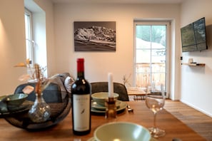Un comedor con una mesa dispuesta para dos personas, una botella de vino y una vela.
