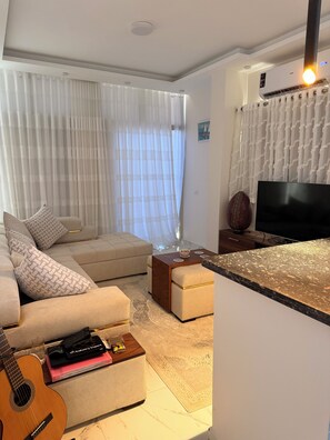 Ein Wohnzimmer mit Sofa, Ottoman, Couchtisch und Fernseher.