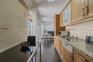 A modern kitchen with wooden cabinets, a granite countertop, and a dining area with a table and chairs. - #387 Family-Friendly Apartment Near the Beach (Armação de Pêra)