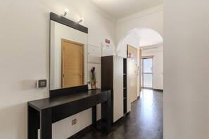 A hallway with a black console table, a mirror, a wooden door, a white refrigerator, and a tiled floor. - #387 Family-Friendly Apartment Near the Beach (Armação de Pêra)