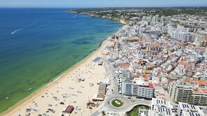 Vista aèria d'una ciutat costanera amb platja, edificis i un mar blau clar.