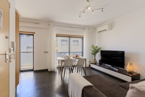 A modern living room with a flat-screen TV, a dining area with a table and chairs, and a sofa. - #387 Family-Friendly Apartment Near the Beach (Armação de Pêra)