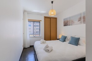 Un dormitori amb un llit, una porta de fusta, una finestra i decoració mural.
