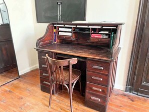 A wooden desk with drawers and a chair, a blackboard, and a shelf with books and a green object. - Charming Studio in the Heart of Bordeaux (Bordeaux)