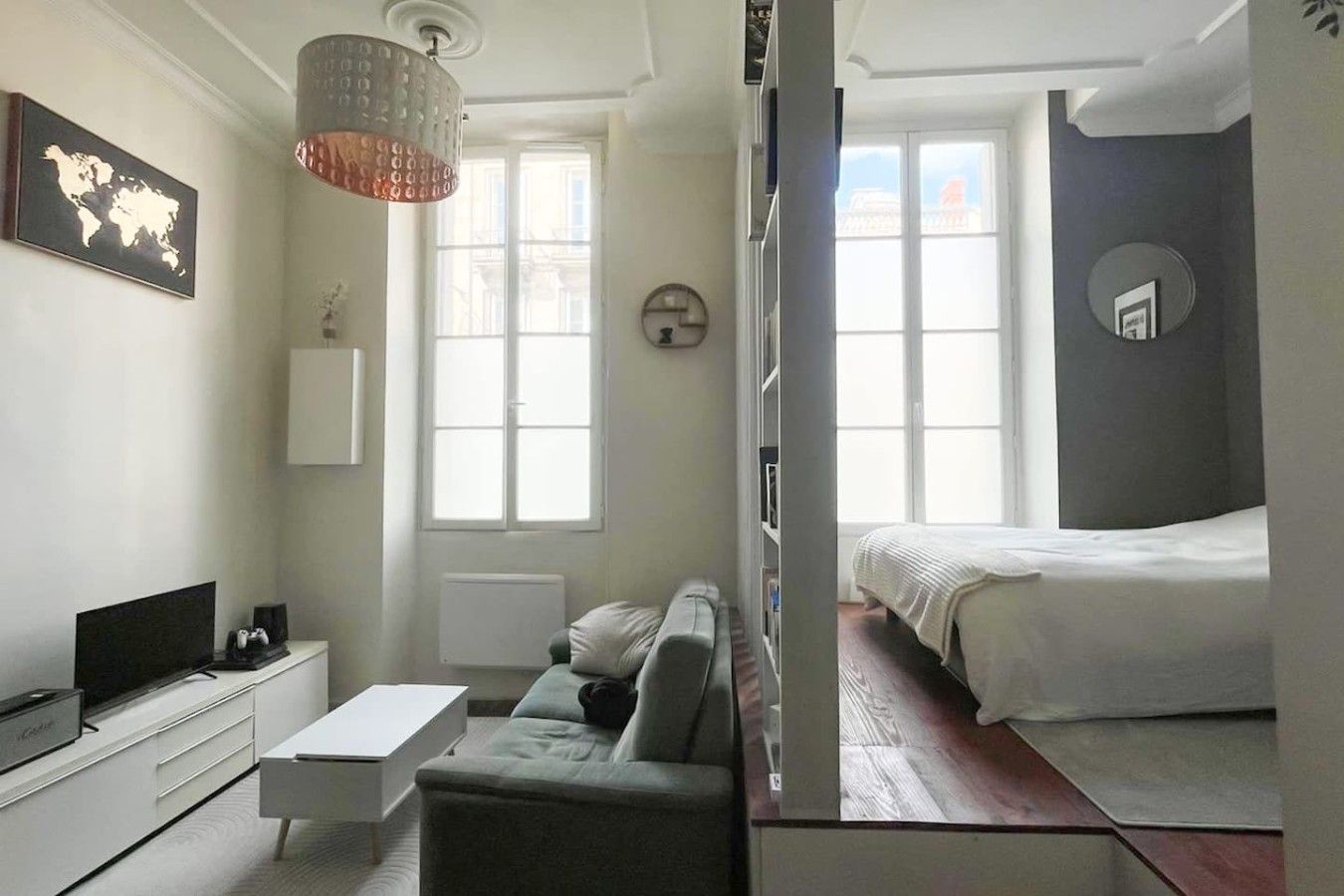 A modern hotel room with a bed, a sofa, a desk, and a television.