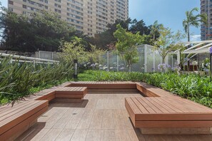Ein Dachgarten mit Holzpflanzgefäßen, einer Pergola und Blick auf hohe Gebäude.