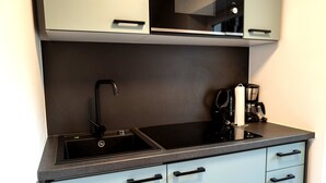 Uma cozinha moderna com pia preta, cafeteira e forno embutido.