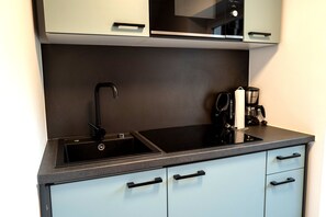 Eine moderne Küche mit einem schwarzen Spülbecken, einer Kaffeemaschine und einem eingebauten Backofen.