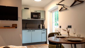 Cozinha compacta com micro-ondas, cafeteira e área de jantar com mesa posta para dois.