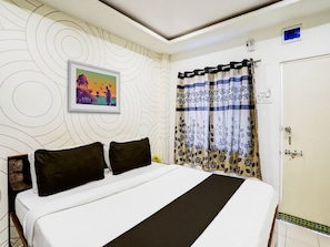 A bedroom with a bed, a picture on the wall, a curtain, and a door.