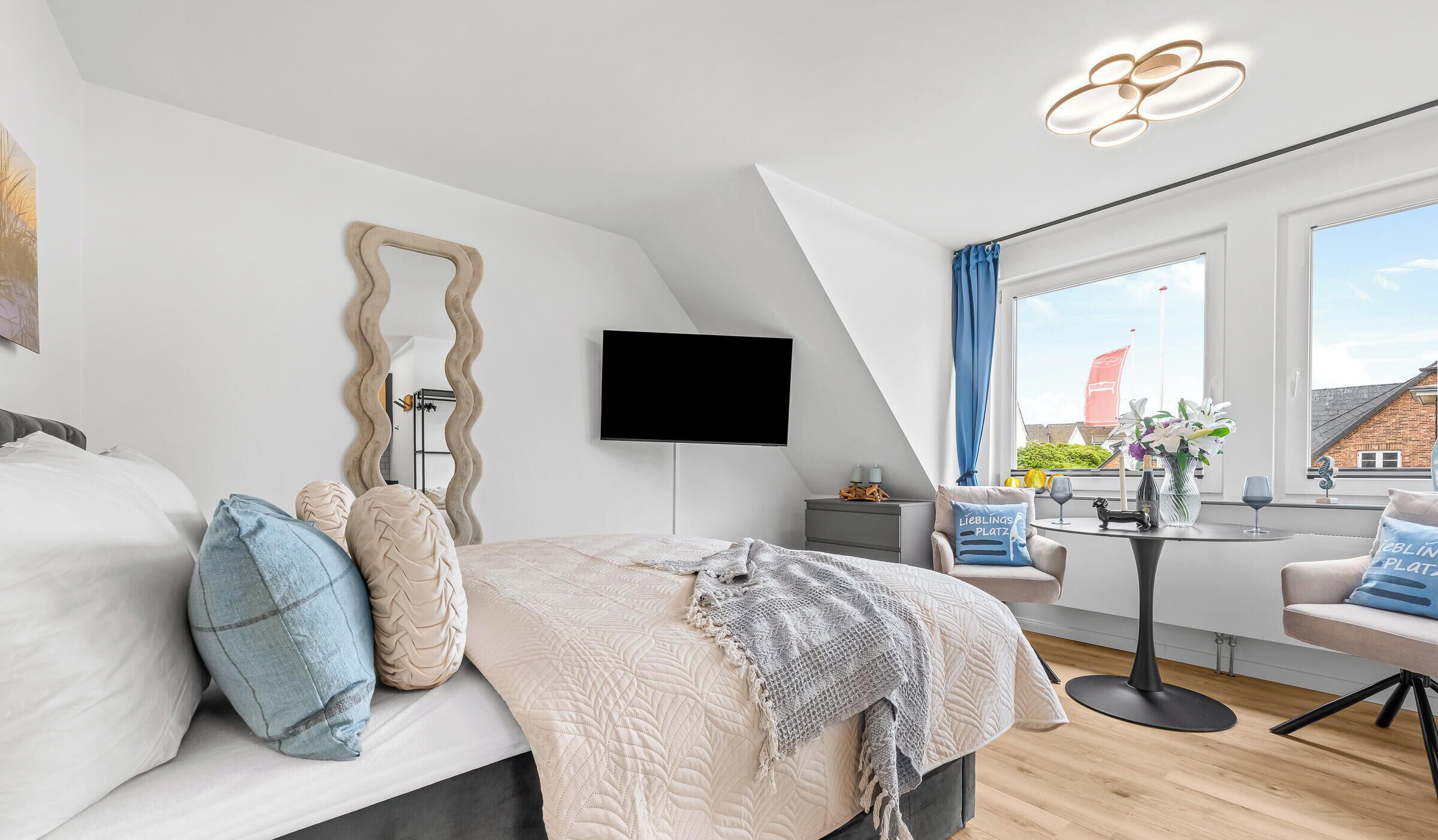 Een moderne slaapkamer met een bed, een flatscreen televisie, een eettafel en uitzicht op buiten.