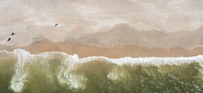 Ein sandiger Strand mit Wellen und Fußspuren.