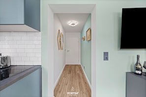 A modern kitchen with a toaster, a wooden floor, and a flat-screen TV on the wall. - Modern, newly renovated vacation rental in the heart of Hörnum on SyltModern, newly (Hörnum (Sylt))