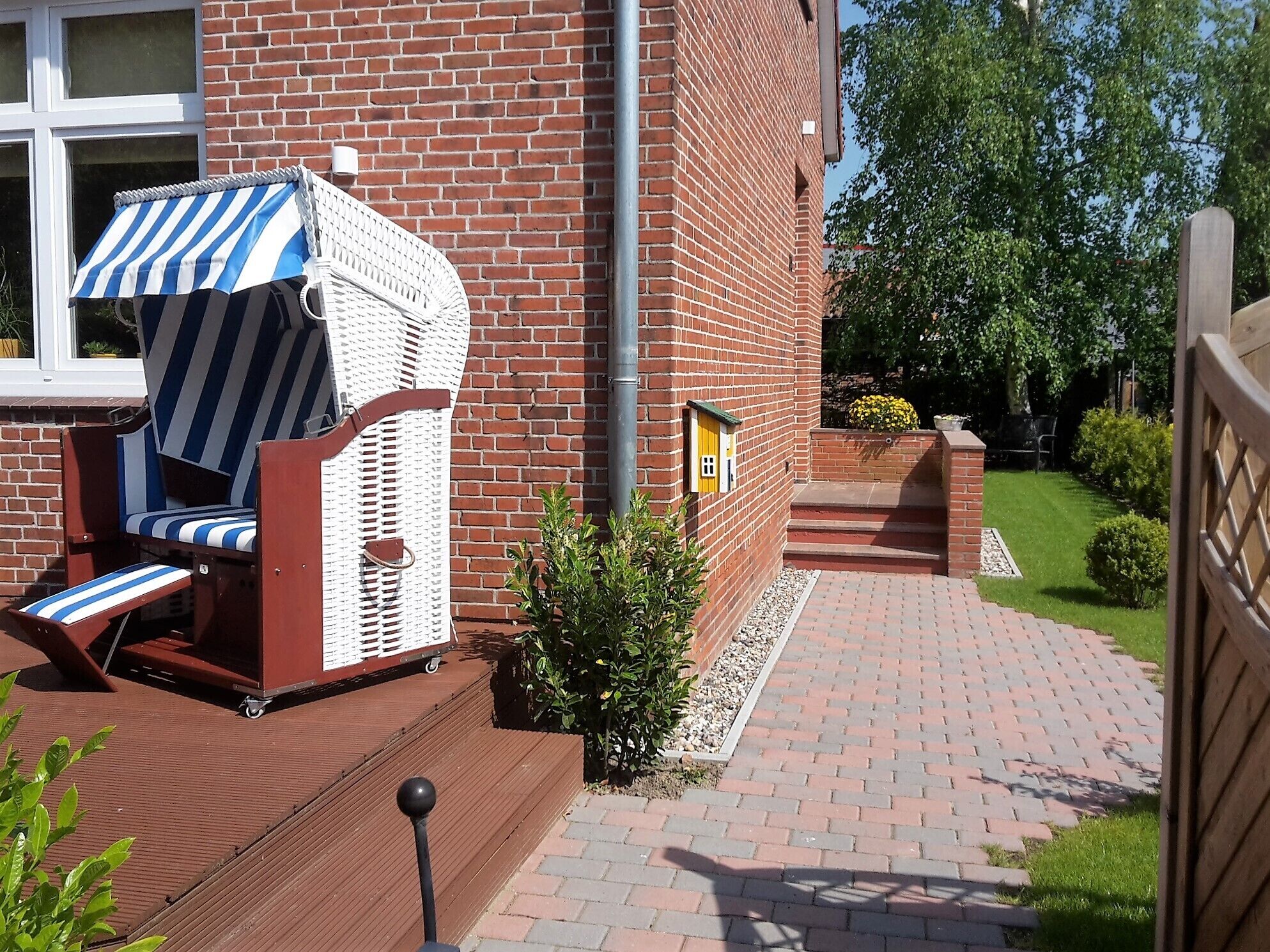 A brick building with a covered outdoor seating area, a small garden, and a paved walkway.