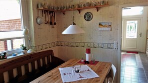 Ein Essbereich mit Holztisch, Bank und hängenden Küchenutensilien.